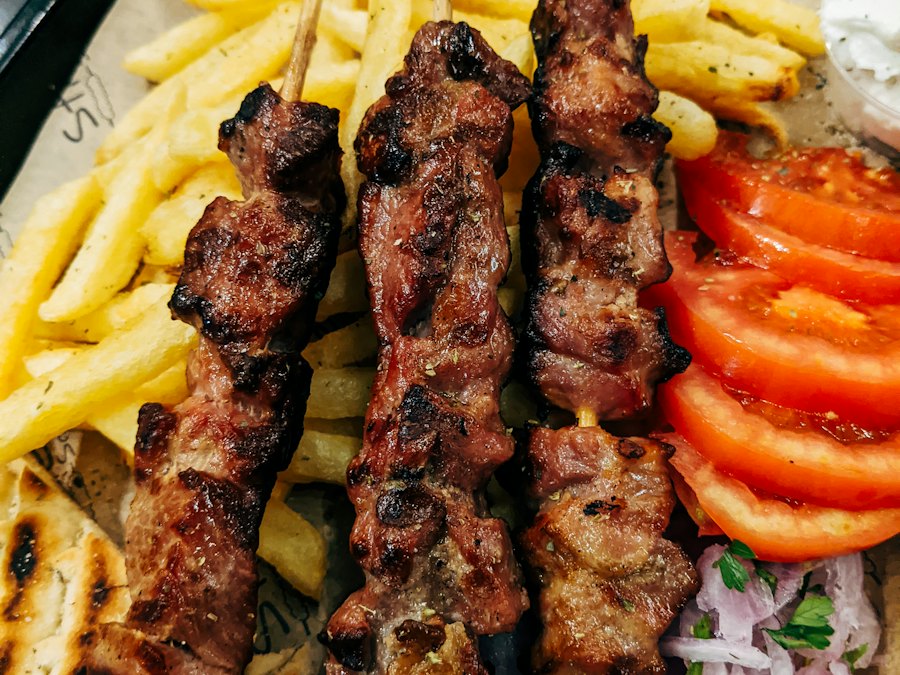 Grilled souvlaki skewers with fries, tomatoes, red onion and pita
